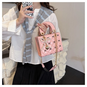 Close-up of pink patent leather handbag with quilted pattern and pearl bow charm detail