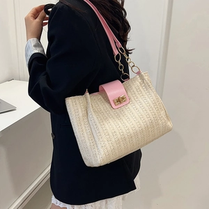 Woven straw shoulder bag with pink leather trim and gold chain strap shown on model