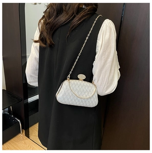 Silver glitter evening clutch bag with gold chain strap shown on model's shoulder