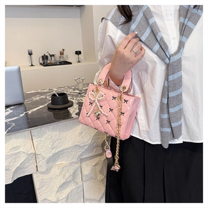 Detail of pink patent leather quilted handbag with pearl bow charm and heart pendant