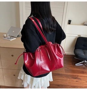 Vue détaillée d'un grand sac cabas rouge brillant avec nœuds porté par un mannequin