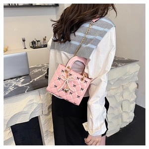 Pink patent leather quilted bag with black bows and pearl butterfly decoration