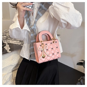 Close-up of pink patent leather handbag featuring diamond quilting and pearl bow charm