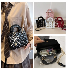 Detail of glossy patent leather handbag with quilted pattern, pearl bow, and heart charm