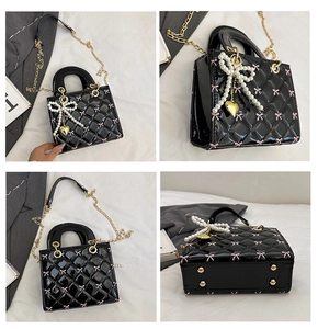 Close-up of quilted patent leather bag with pink bows and pearl charm accessory