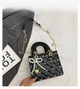 Macro detail of quilted patent leather bag with pearl bow and golden heart charm