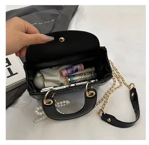 Interior view of black patent leather quilted bag with pearl charm and chain strap