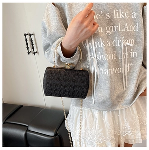 Detail of black woven evening bag with gold ring handle and chain strap on model
