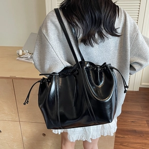 Sac fourre-tout noir brillant avec détail de nœud présenté de profil sur un mannequin