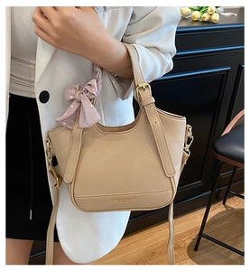 Détail du sac seau en cuir abricot avec nœud rose à pois et finitions métalliques dorées