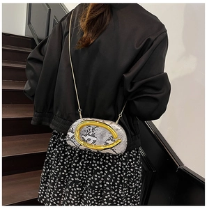 Detail van crossbodytas met slangenprint en een groot goudkleurig metalen handvat