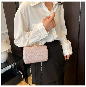 Pink sequin evening clutch bag with gold handle and chain strap worn by a model