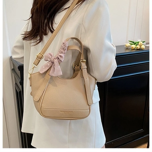 Détail du sac seau beige avec texture litchi, foulard rose et finitions dorées