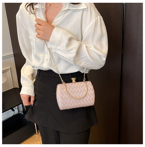 Macro detail of pink chain bag with woven texture, gold handle and metal ball clasp