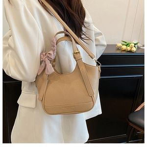 Détail du sac seau beige à motif litchi avec nœud à pois roses et texture en cuir