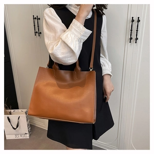 Close-up of brown faux leather tote bag showing smooth texture and adjustable shoulder strap