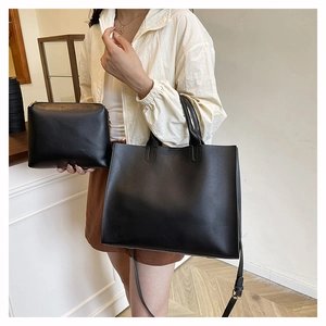 Detail shot of black leather tote bag with matching pouch and gold metal hardware accents