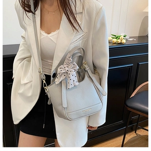 Détail du sac seau en cuir gris clair avec nœud à pois et boucle métallique dorée