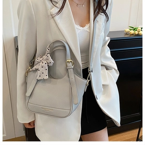 Détail du sac à main en cuir gris clair avec foulard en soie et finitions dorées chic