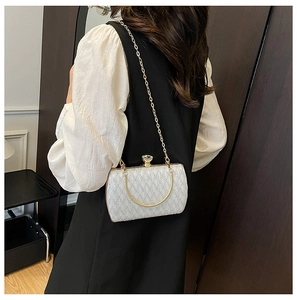 Detail of elegant white evening bag featuring gold handle and crystal buckle lock