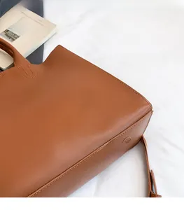Detail shot of brown PU leather tote bag showing neat stitching and textured material surface