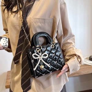 Glossy black patent leather handbag with diamond quilting and pearl bow charm