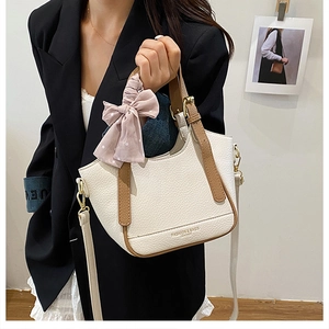 Détail du sac seau en cuir grainé blanc cassé avec poignée marron et nœud rose