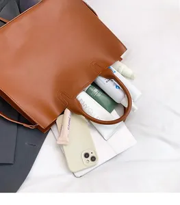 Detailed interior of a large brown tote bag showing ample space for tablets and cosmetics