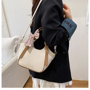 Détail du sac seau en cuir crème avec bordure marron et foulard en soie à pois roses