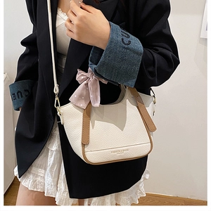 Détail d'un sac à main en cuir crème avec poignées marron et nœud écharpe à pois roses