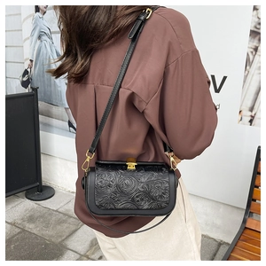 Detail of vintage black crossbody bag with embossed floral patterns and gold hardware