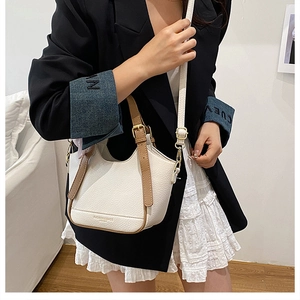 Détails du sac seau en cuir grainé blanc avec bandoulière marron et boucles dorées