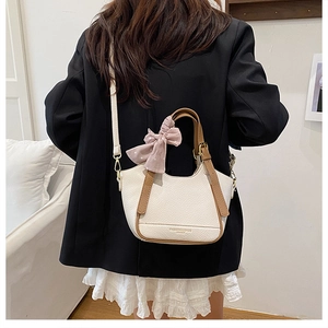 Détail d'un sac à main crème en similicuir avec lanières marron et nœud à pois roses