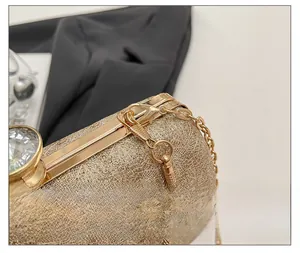 Detailed close-up of a gold evening clutch with lace texture and a large brilliant gemstone