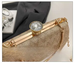Detail of gold evening clutch featuring leaf texture, crystal clasp, and snake chain strap