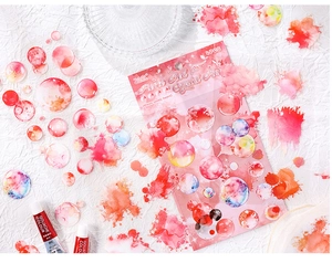 Close-up of red watercolor round PET stickers with artistic stationery packaging