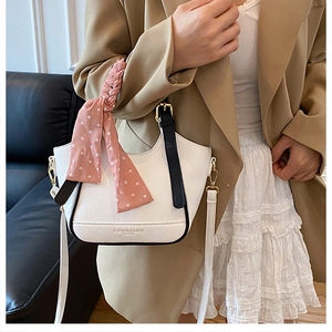 Détail du sac à main en cuir blanc avec un foulard rose à pois sur la poignée