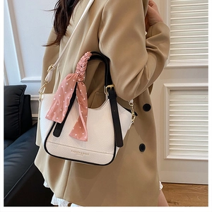 Détail du sac seau en cuir grainé blanc avec foulard à pois roses porté par un mannequin