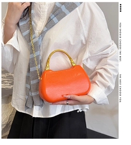 Detail of orange faux leather box bag featuring gold bamboo handle and chain strap