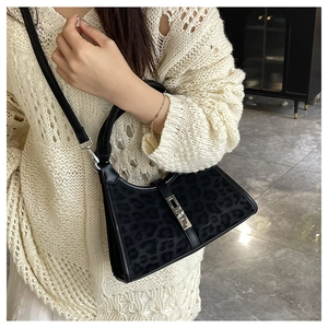 Detail view of black leopard print shoulder bag with silver metallic buckle on a model