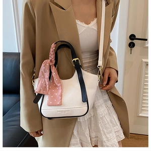 Sac seau en cuir grainé blanc avec poignée noire et détail de foulard en soie à pois roses