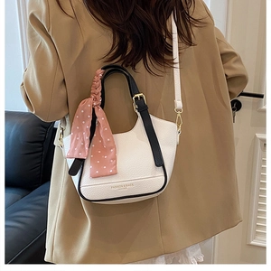 Sac seau en cuir grainé avec poignée contrastée et foulard porté par un mannequin