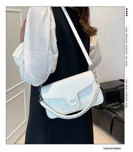 Detail of white cross-body saddle bag with textured leather and C-shaped metal buckle
