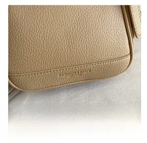 Détail macro du sac en cuir grainé montrant les coutures fines et le logo doré