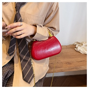 Close-up of bright red patent leather handbag with gold chain strap and horn-shaped clasp