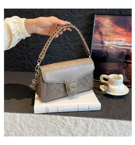 Detail of grey-brown handbag showing luxury lattice texture and silver C-shaped buckle