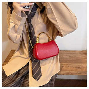 Detail of red leather box bag with gold spiral handle and metal chain for women