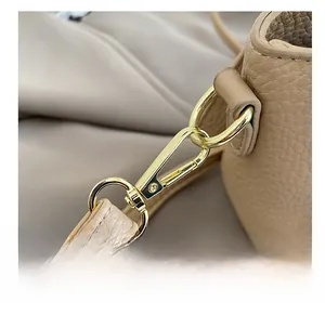 Détail du crochet métallique doré poli et du connecteur sur un sac à main en cuir beige