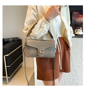 Detail of grey crossbody bag with woven texture, silver C-buckle and braided handle