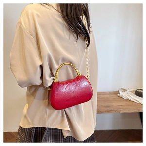 Detail of red patent leather handbag featuring gold bamboo-shaped metal handle and chain strap